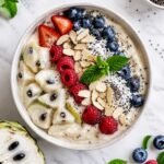 sugar apple smoothie bowl topped with berries, chia seeds, coconut and almonds